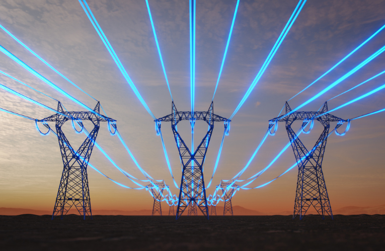 Steel transmission towers stretch across a desert plain at sunset while glowing blue strands symbolize data-intensive artificial intelligence increasing power consumption.